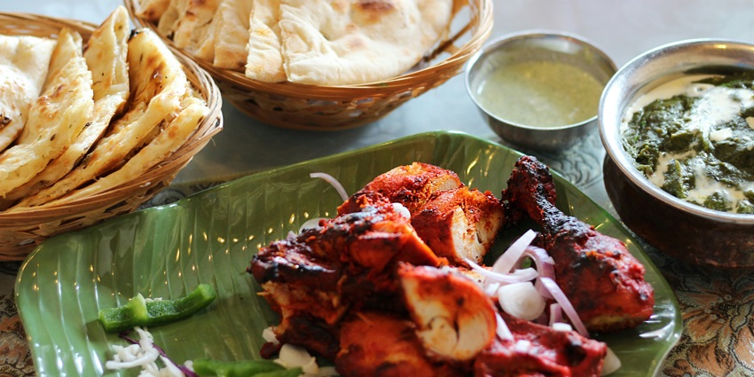 Image of chicken tandoori and chapatti served on banana style plates in a restaurant