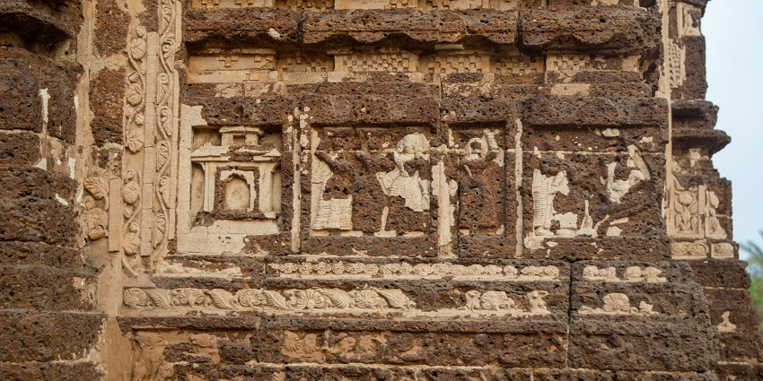 The weathered walls of an ancient temple due to the passage of time. The historic designs are also weathered and ruined.