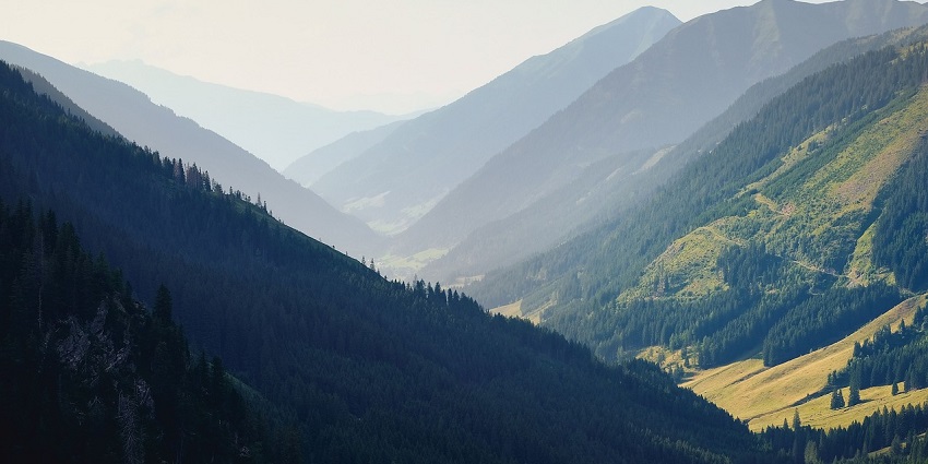 A stunning view of a mountain range and valley at dusk, enveloped in a gentle haze.