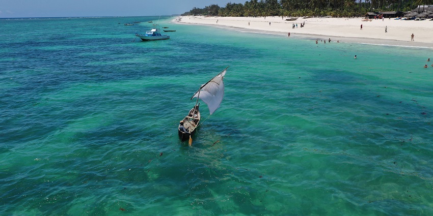 Aerial view of boats sailing in the crystal turquoise water to the golden shores of the Kadmat beach