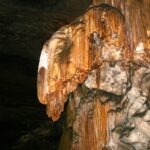 Stalagmites of gold metallic colour formed in a dark cave along with several other rocks