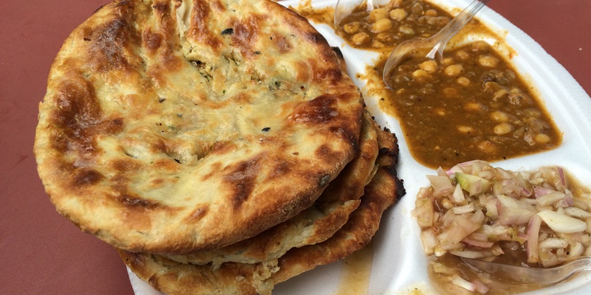 Stuffed naan served with chole curry and onions on the side making a full delicious meal