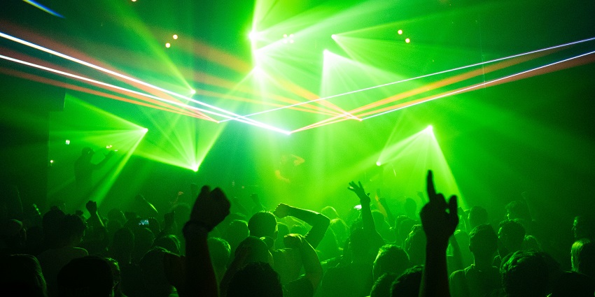 A group of people dancing at a nightclub under a green-lit ambience