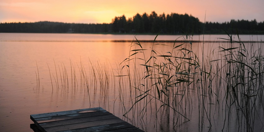 Panoramic view of sunset at the lake, with the sun hues reflecting in the water