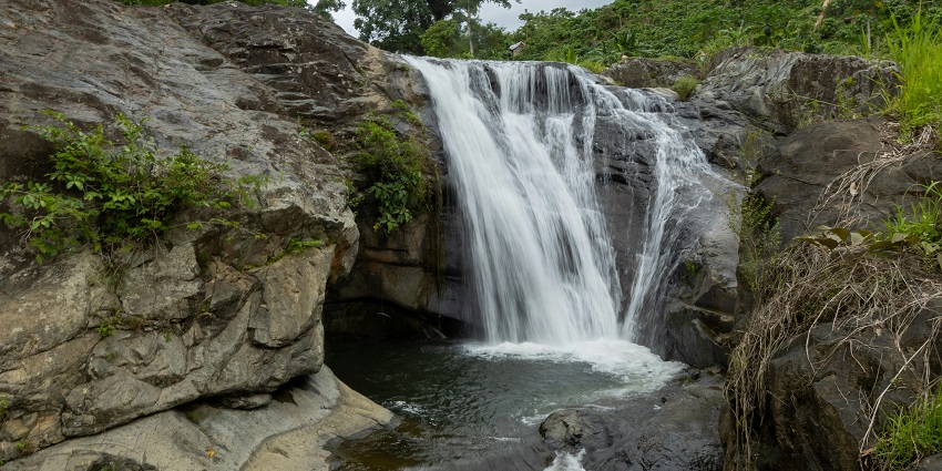 A picture of a waterfall surrounded by rocky terrains and greenery