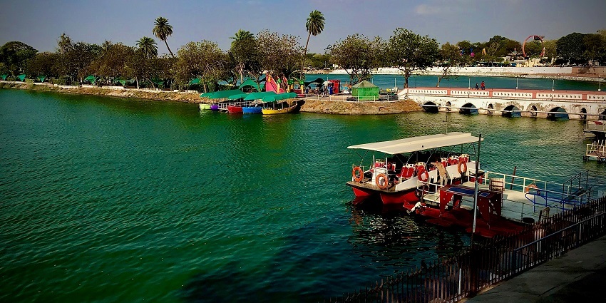 Image of Kankaria Lake and boat view on a clear water surrounded by trees under blue sky