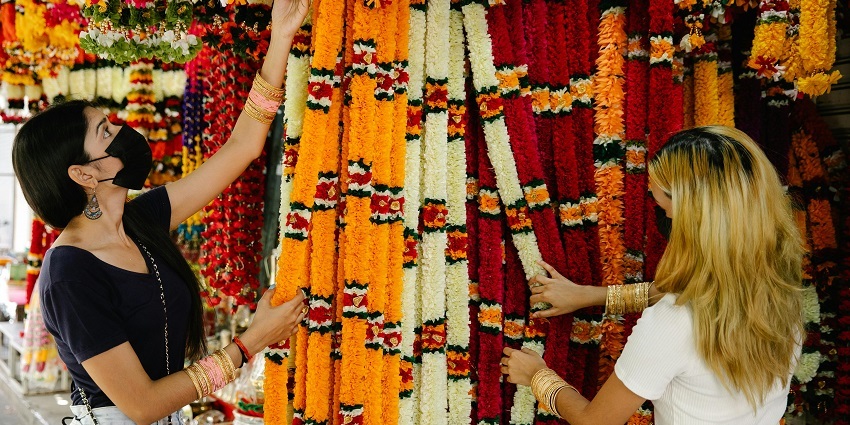 Two women looking through traditional handicraft items and vibrant garlands on display