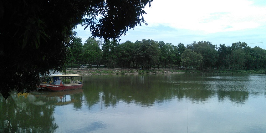 A picture of a lake in Karnal with trees and greenery on the shore