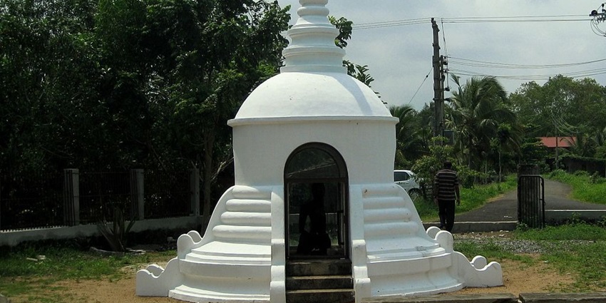 A stone sculpture of Karumadikuttan, a famous Jain figure, in a serene setting.