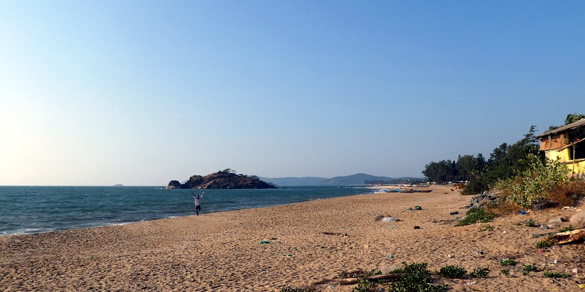 A picture of a beach in Karnataka taken during daytime with a small rocky island in the background