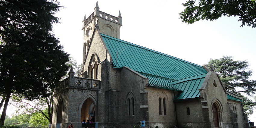 Image of Christ Church in Kasauli surrounded by lush green mountains and long trees