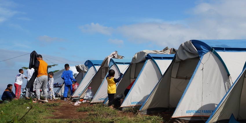 A family enjoying camping in Solan with tents, camping chairs, and a picnic table on a field.