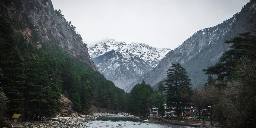 View of Kasol, showcasing lush green mountains and a serene river flowing through the valley.