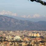 A panoramic view of Kathmandu, Nepal, showcasing the city's streets and surrounding hills.