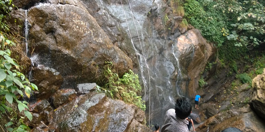 A glimpse of the cascading Katiki Waterfalls surrounded by emerald-green vegetation.