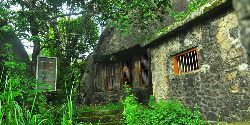 A picture of a historical Temple with ancient architecture, surrounded by trees and greenery