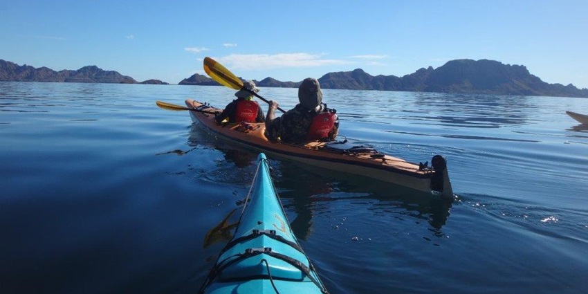 A person kayaking on a serene lake in surrounded by mountains like in Calangute, Goa.