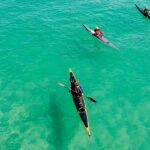 A breathtaking view of three colourful kayaks on an azure water body during the daytime.