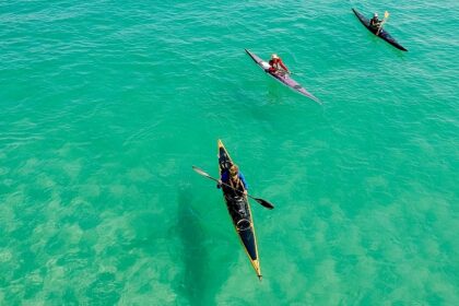 A breathtaking view of three colourful kayaks on an azure water body during the daytime.