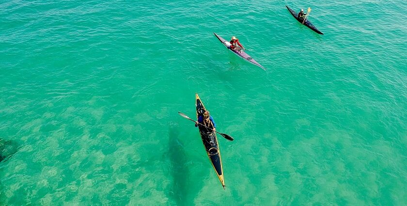 A breathtaking view of three colourful kayaks on an azure water body during the daytime.