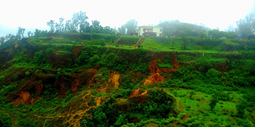 The house at the top of the hills is surrounded by lush greenery.
