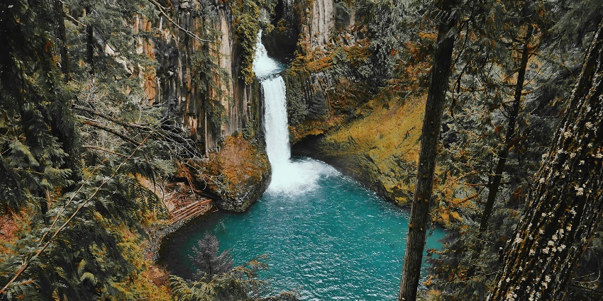 An image of Keoti Falls cascading down rocky terrain, surrounded by dense vegetation