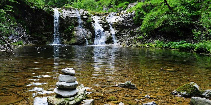 Body of water surrounded by lush green trees, reflecting - hidden waterfalls in Goa