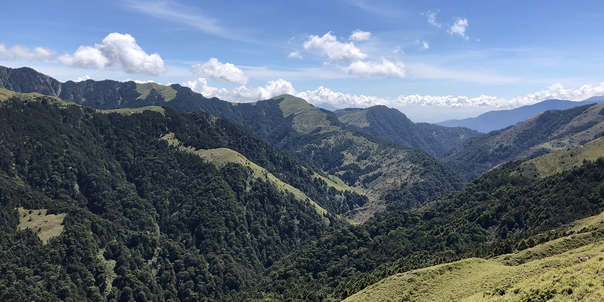Panoramic view of a vast valley surrounded by rugged mountains under a clear blue sky.