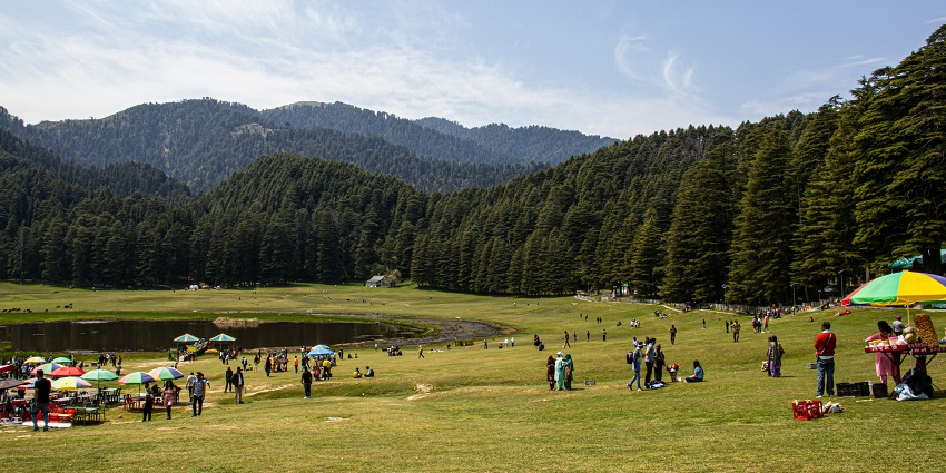 Image of Khajjiar surrounded by lush green trees, field and mountains, people exploring around