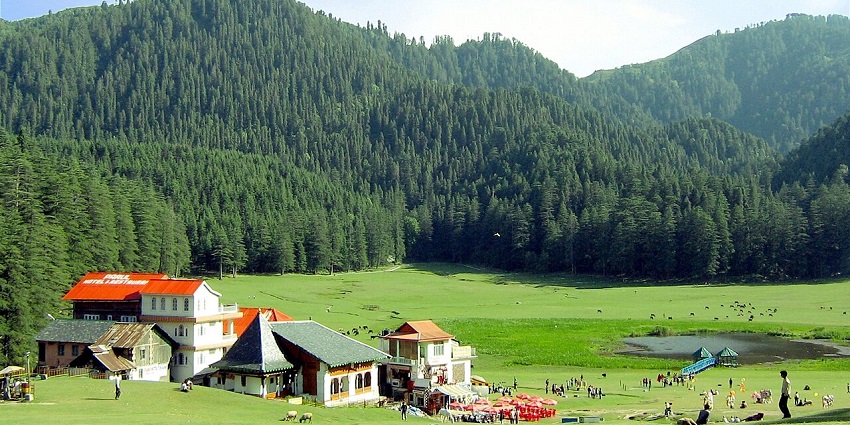 Image of a group of people standing on top of a lush green field - hill stations near Amritsar