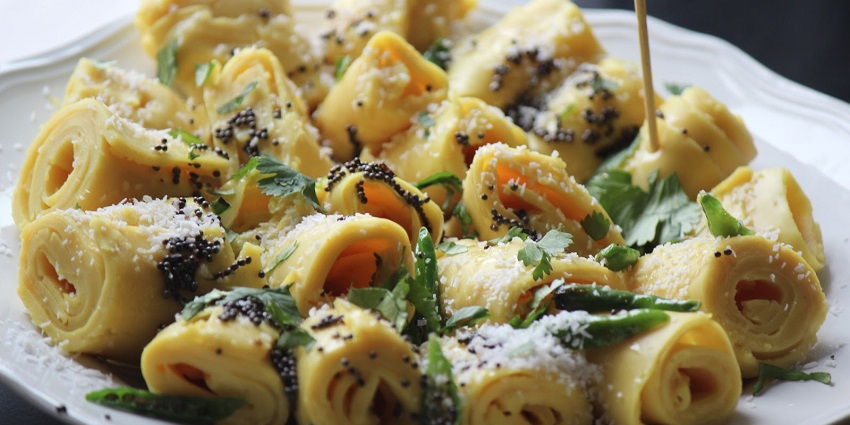 A glimpse of bright-yellow coloured Khandvi, one of the best foods in Ahmedabad.