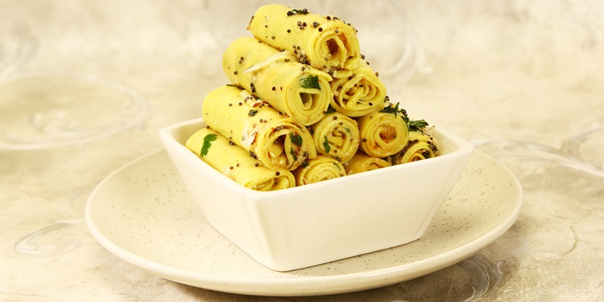 People eat delicate and spicy khandvi, one of the very staple Gujarati snacks.