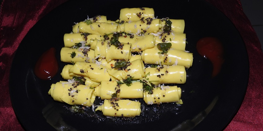 A view of a plate with delicate and spicy khandvi, one of the best street foods in Ahmedabad.