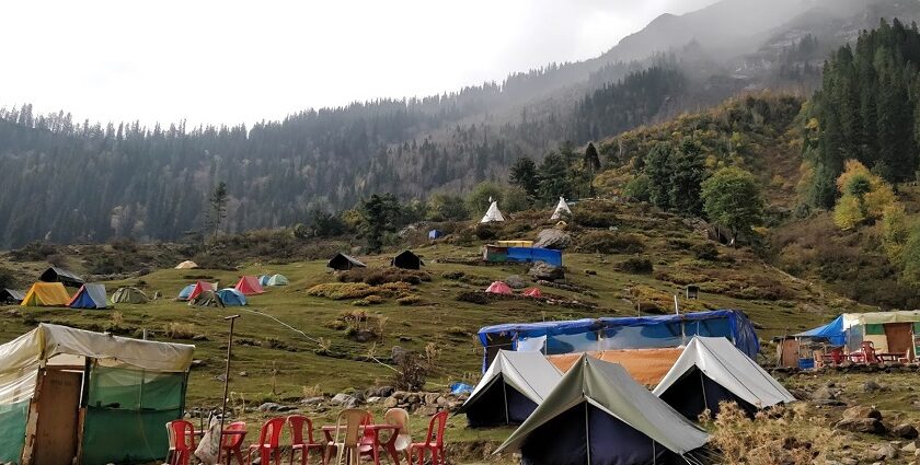 A picture of camps on a trekking site in the Himalayas surrounded by tall mountains