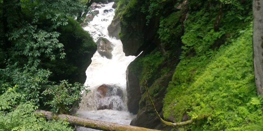 A picture of a small waterfall cascading down the hills on the terrains of Kheer Ganga Trek