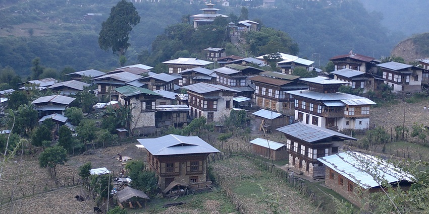An aerial view of a village located on top of a hill in Bhutan with views of lush green valleys