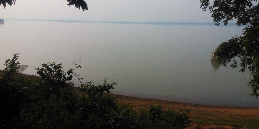 View of one of the lakes in India, surrounded by greenery, similar to Khuntaghat Dham.