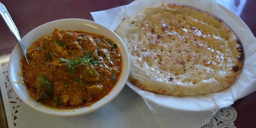 Spicy mutton Khurchan served on a plate, garnished with fresh herbs and onions
