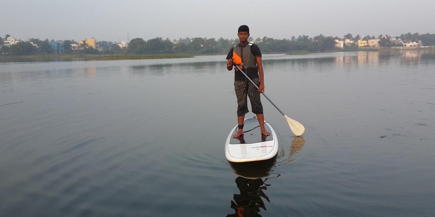A boy learning how to paddleboard.