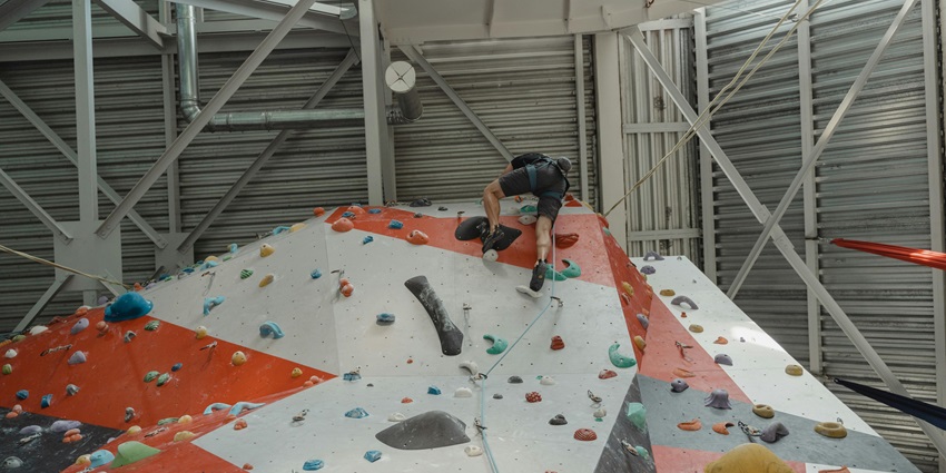 Man in black climbing a wall, capturing the thrill of Kishangarh Adventure Park.
