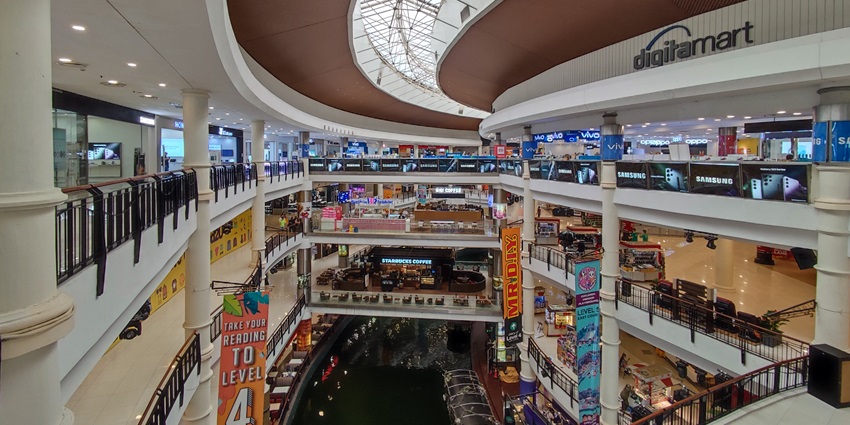 A picture of a massive shopping mall with many brand stores on both sides of the walkway