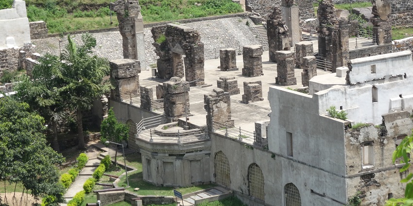 An aerial picture of a fort with a number of pillars standing tall at its roof and a garden in front of it