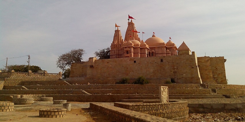 Ancient stone temple perched near a coastal plateau by the sea in western India.