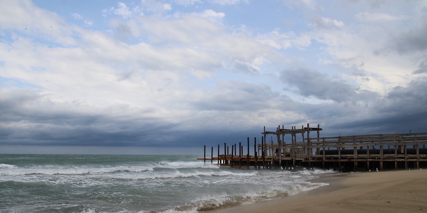 A picture of a beach taken on a cloudy day with a ramp made of wood for people to climb