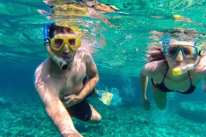 Two people snorkelling underwater exploring marine life capturing themselves in selfie mode.