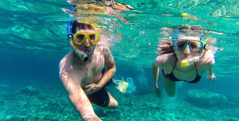 Two people snorkelling underwater exploring marine life capturing themselves in selfie mode.