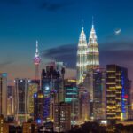 A stunning moonrise over the Kuala Lumpur skyline with the Petronas Towers visible.