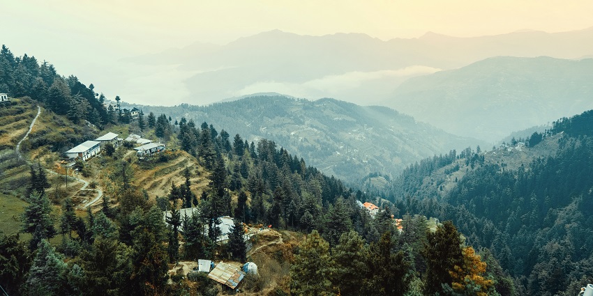 Image of Kufri mountains and it’s twisty road for vehicles, surrounded by lush greenery.