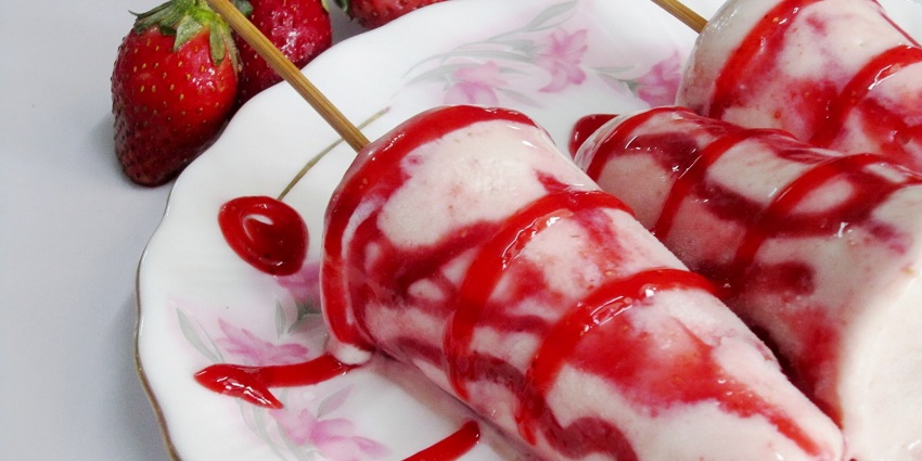 Image of delicious strawberry kulfi served on a white plate with red strawberry syrup on top