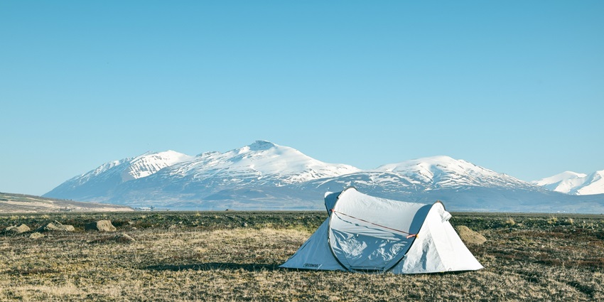A cosy campsite with a white tent, nestled in a peaceful, green forest clearing.